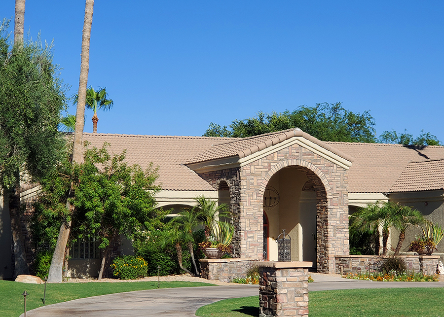 Newly constructed house with tile roof, stone front, and palm trees