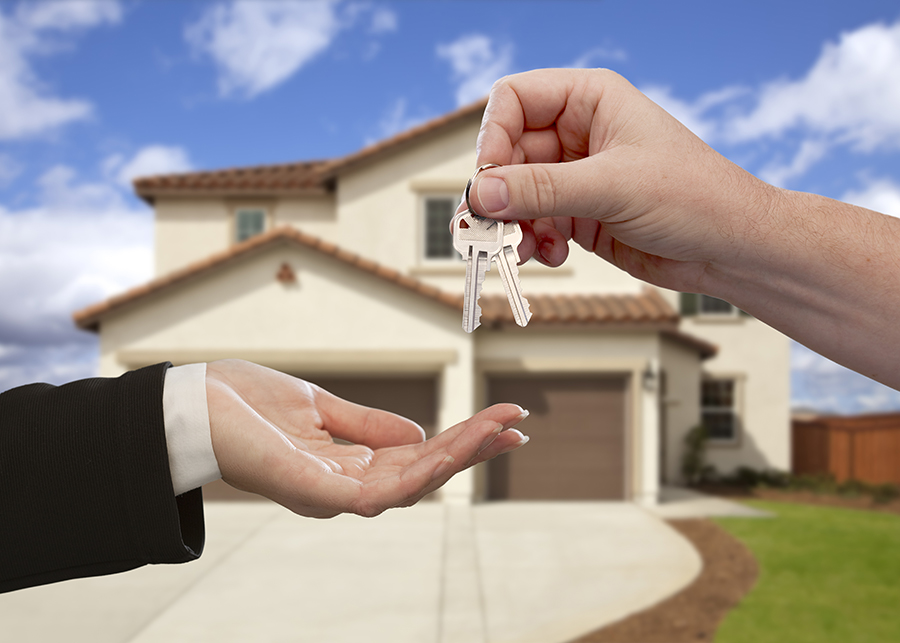 Hands Handing Over the House Keys in Front of a New Home Inspection Services