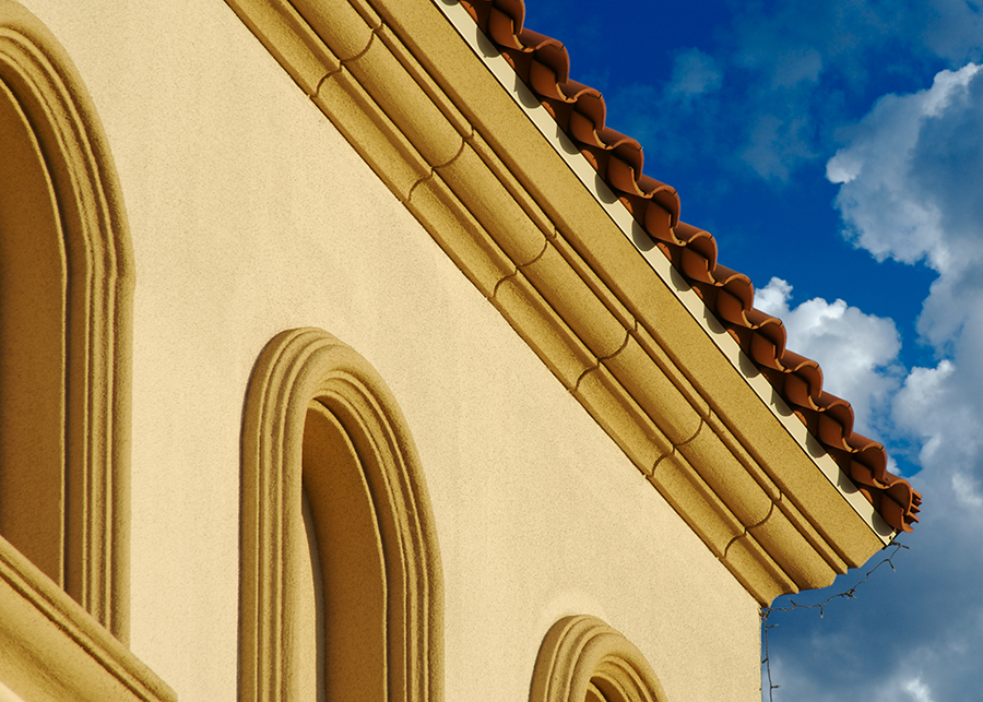 Looking up at a house with stucco walls and tile roof of a house